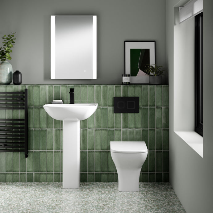 Bathroom interior with green tiled wall, white sink, and toilet.