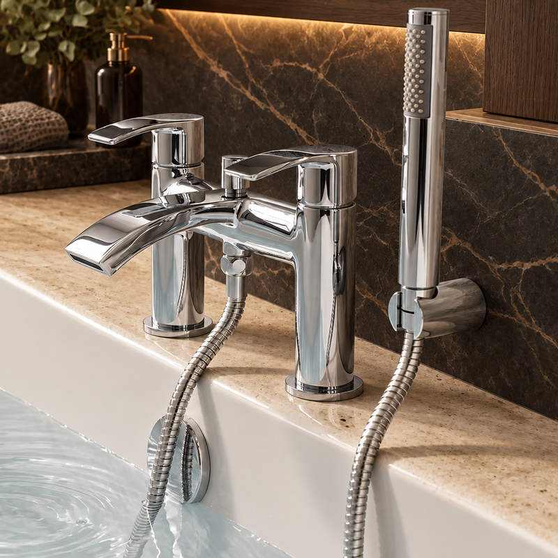 Chrome bath shower mixer with hand shower and hose against dark veined marble, warm lighting and a pale travertine bath ledge